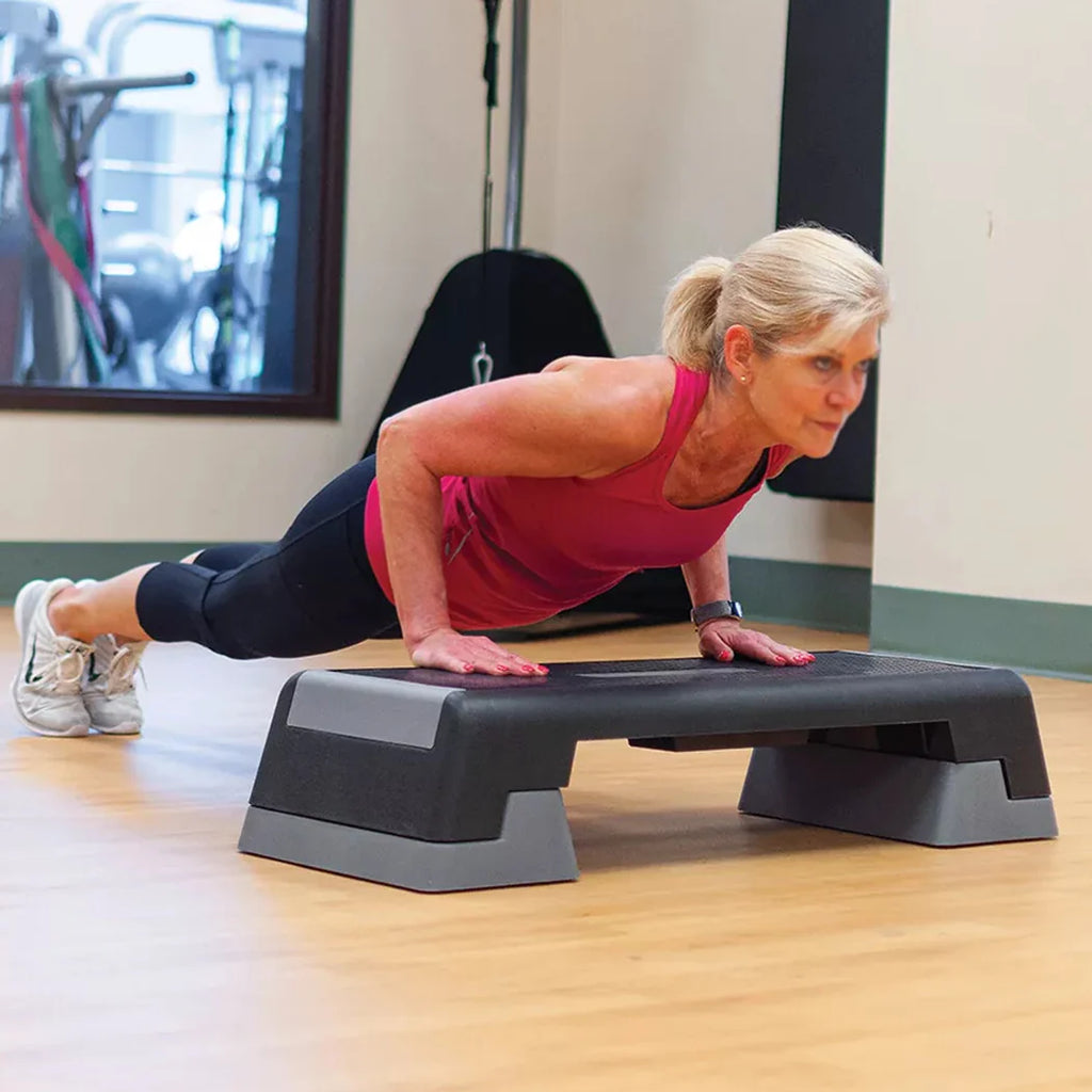 Woman exercising on a step platform in a gym setting