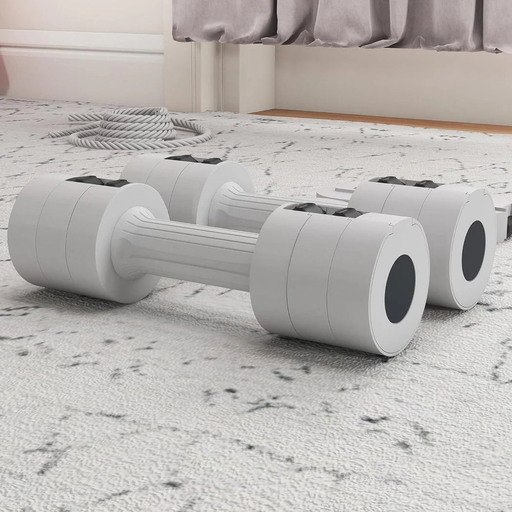 White dumbbells on a carpeted floor with a bed in the background