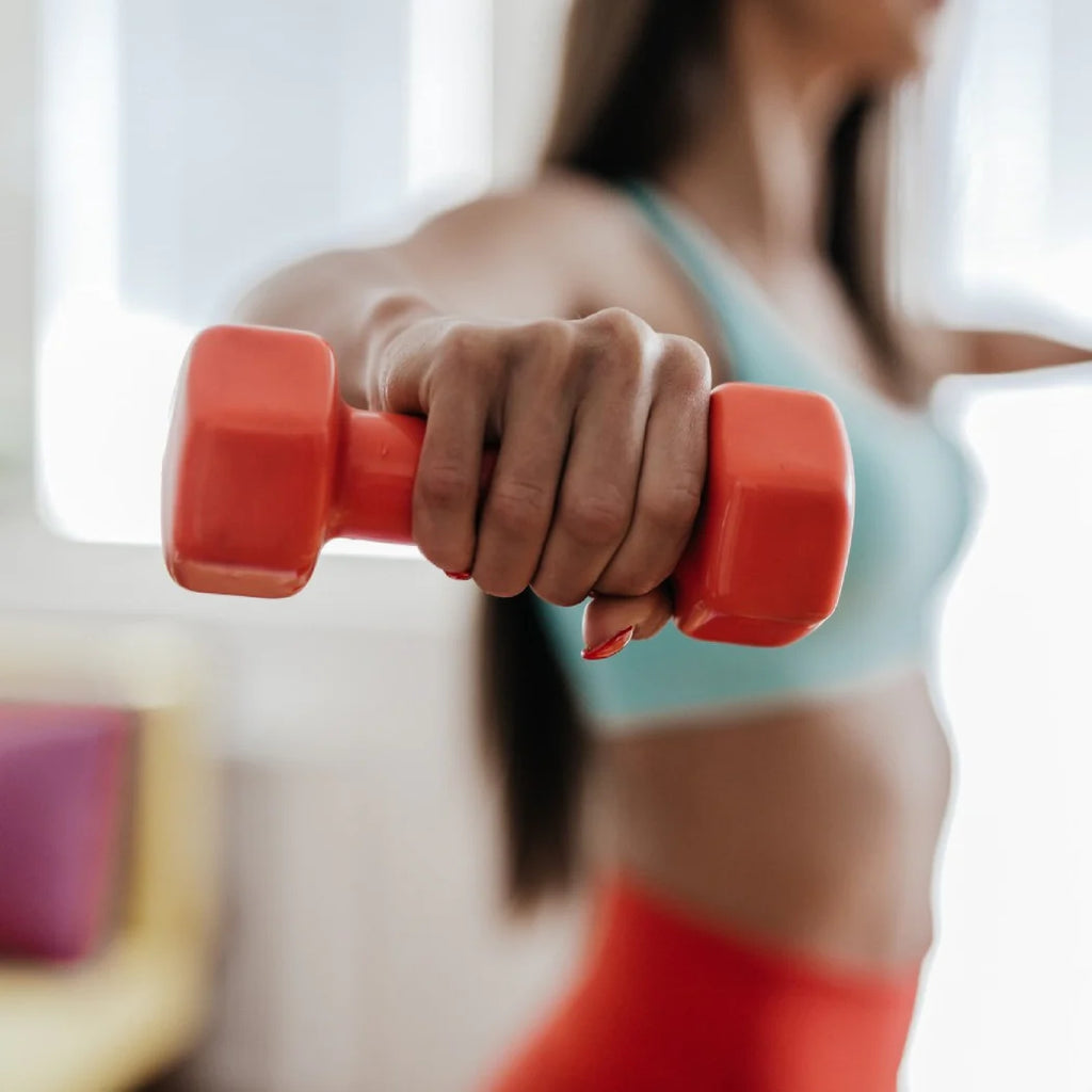 Person holding a red dumbbell with a blurred background