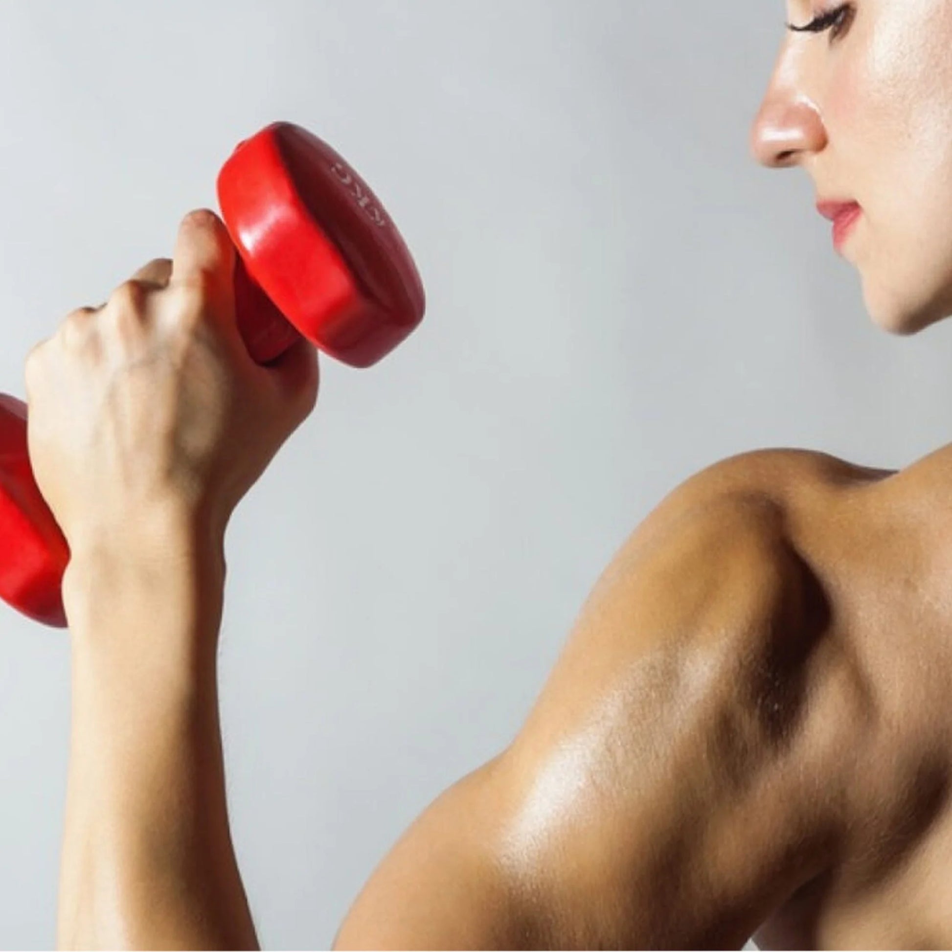 Person lifting a red dumbbell against a gray background