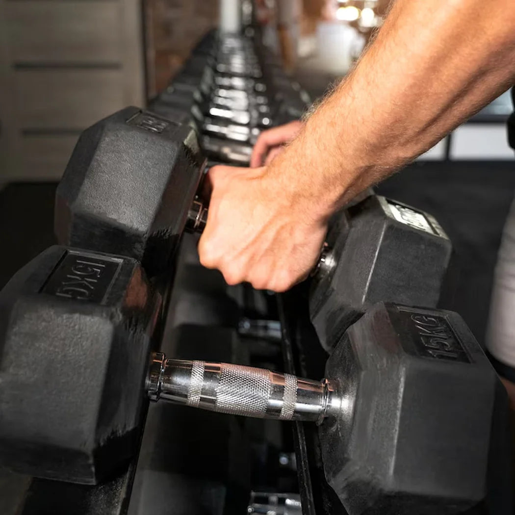 Person selecting a dumbbell from a rack in a gym setting