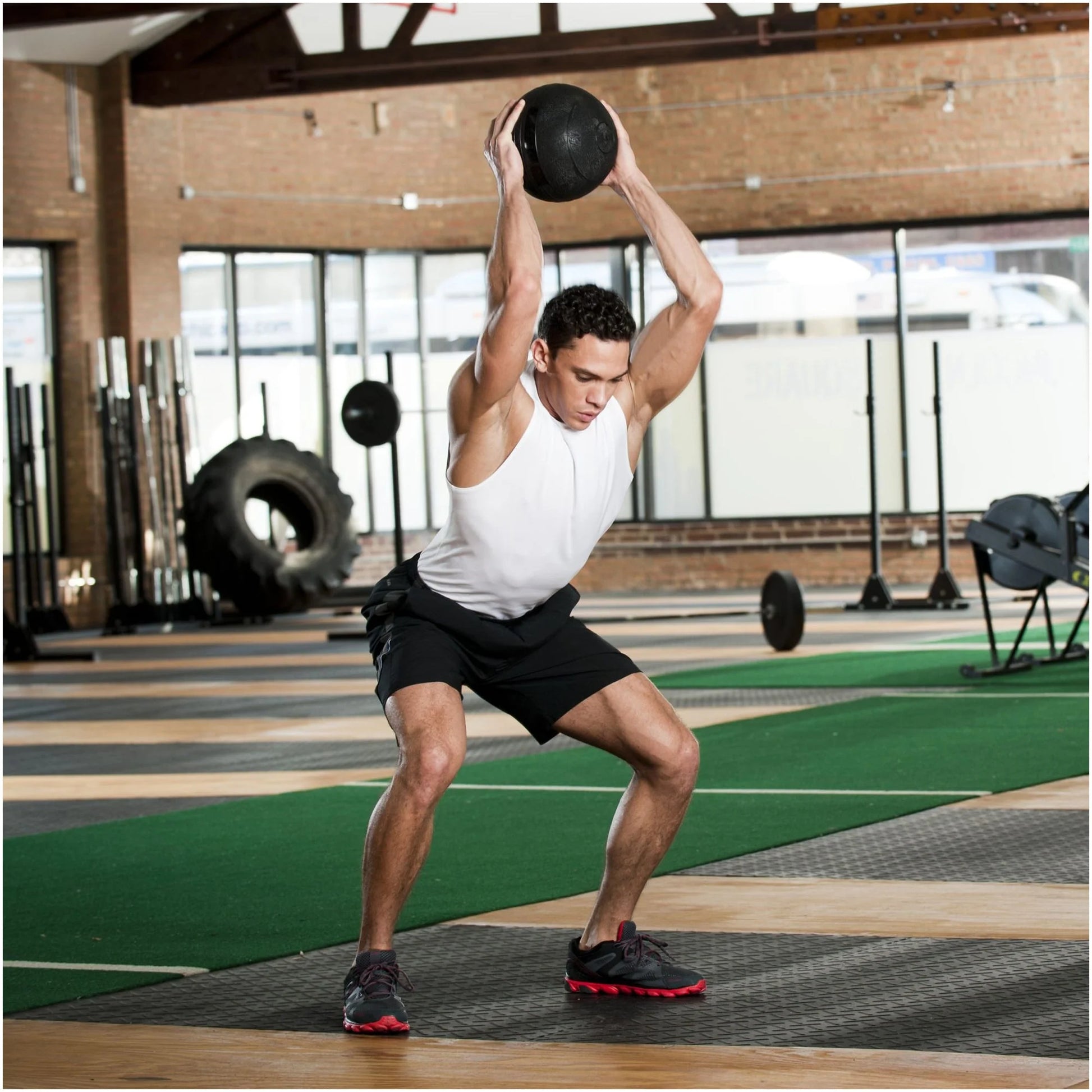 Man lifting a medicine ball in a gym setting