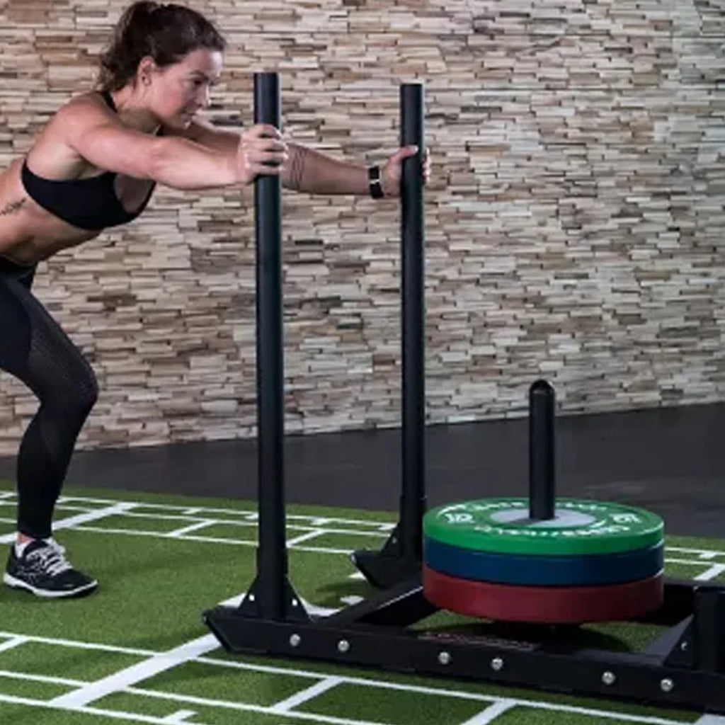 Person using a weight training machine with weights on a sports field.