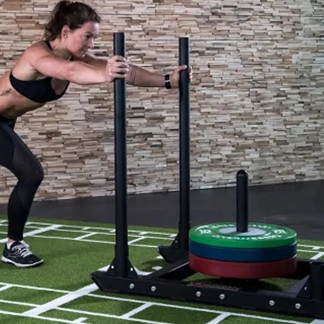 Person using a weight training machine with weights on a sports field.