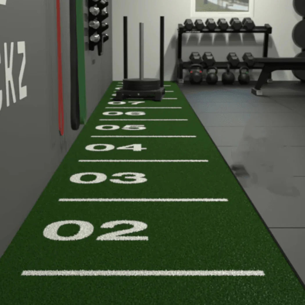 Green sports field with number markings in a gym setting