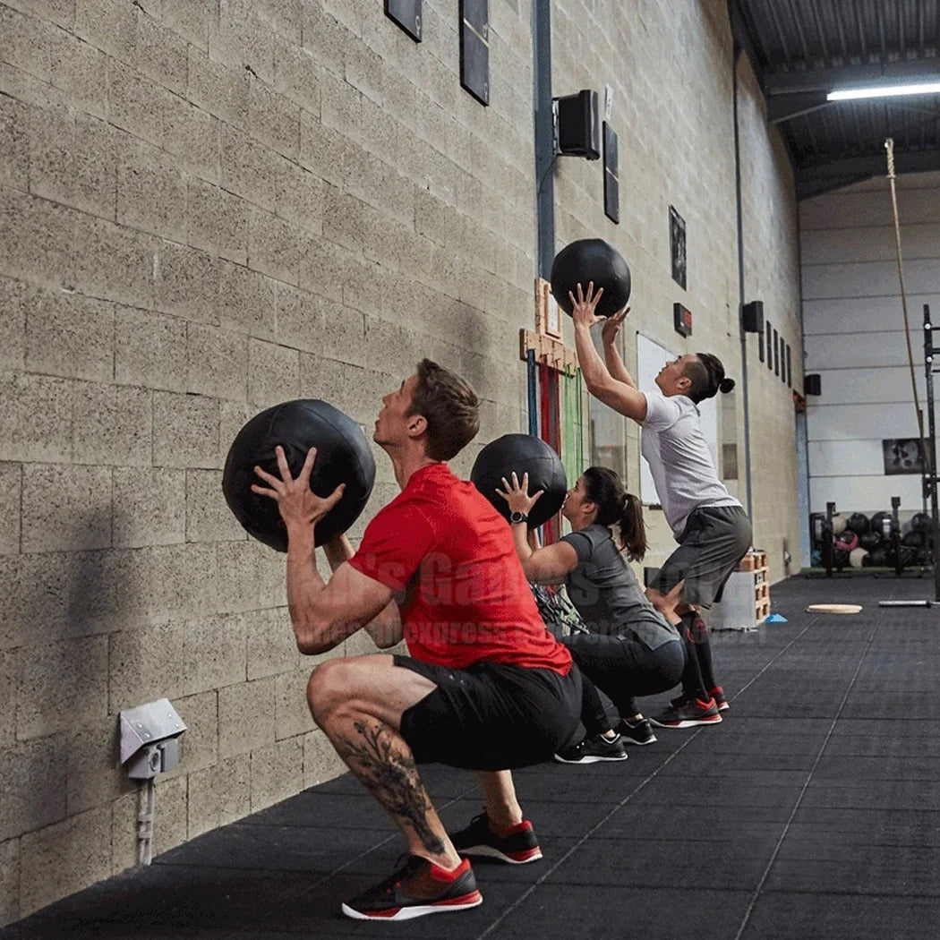 Group of people exercising with medicine balls in a gym setting.