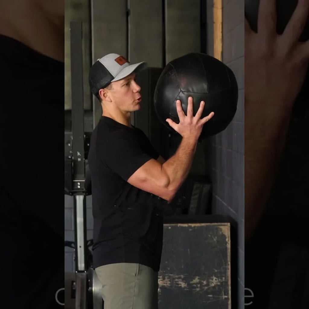 Person holding a medicine ball in a gym setting